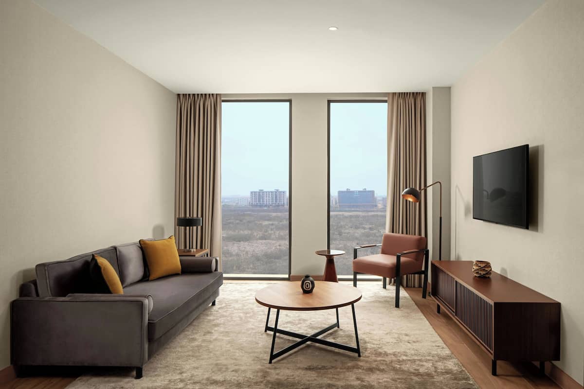 A modern living room with a sofa, armchair, coffee table, and TV.