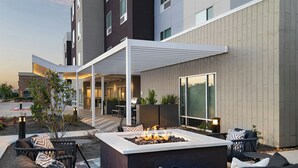 An outdoor seating area with a fire pit, wicker furniture, and a covered patio. - TownePlace Suites by Marriott® Houston Tomball (Tomball)