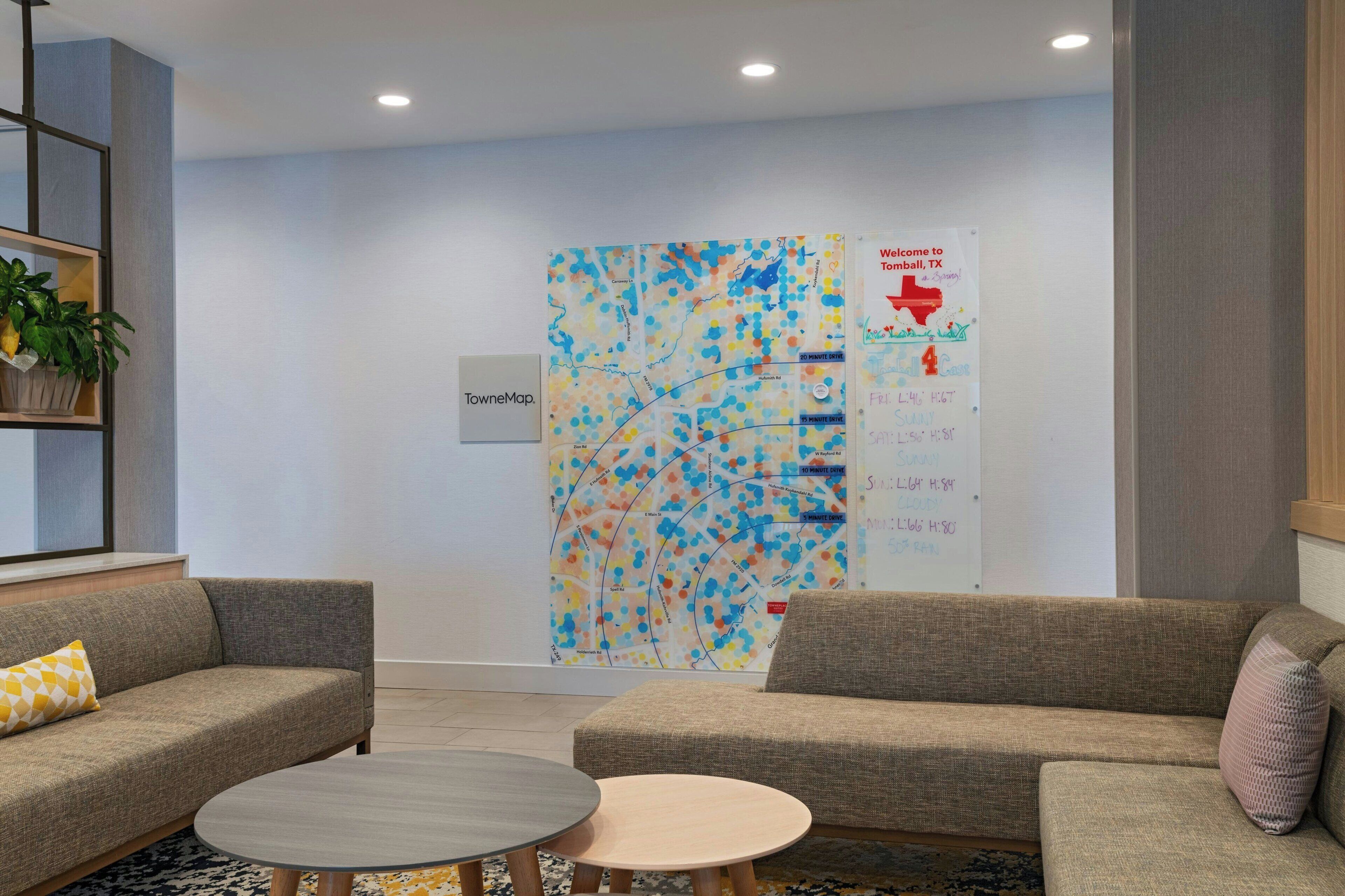 Un espace d’attente moderne, doté de deux canapés, d’une petite table et d’une carte colorée accrochée au mur.
