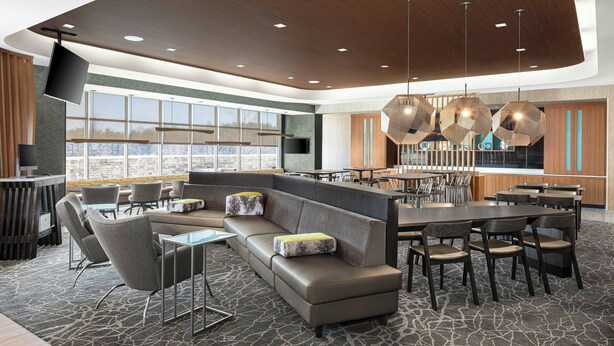 A modern hotel lobby with a large seating area, a bar, and a large window offering a city view. - Springhill Suites By Marriott Raleigh Garner (Garner)