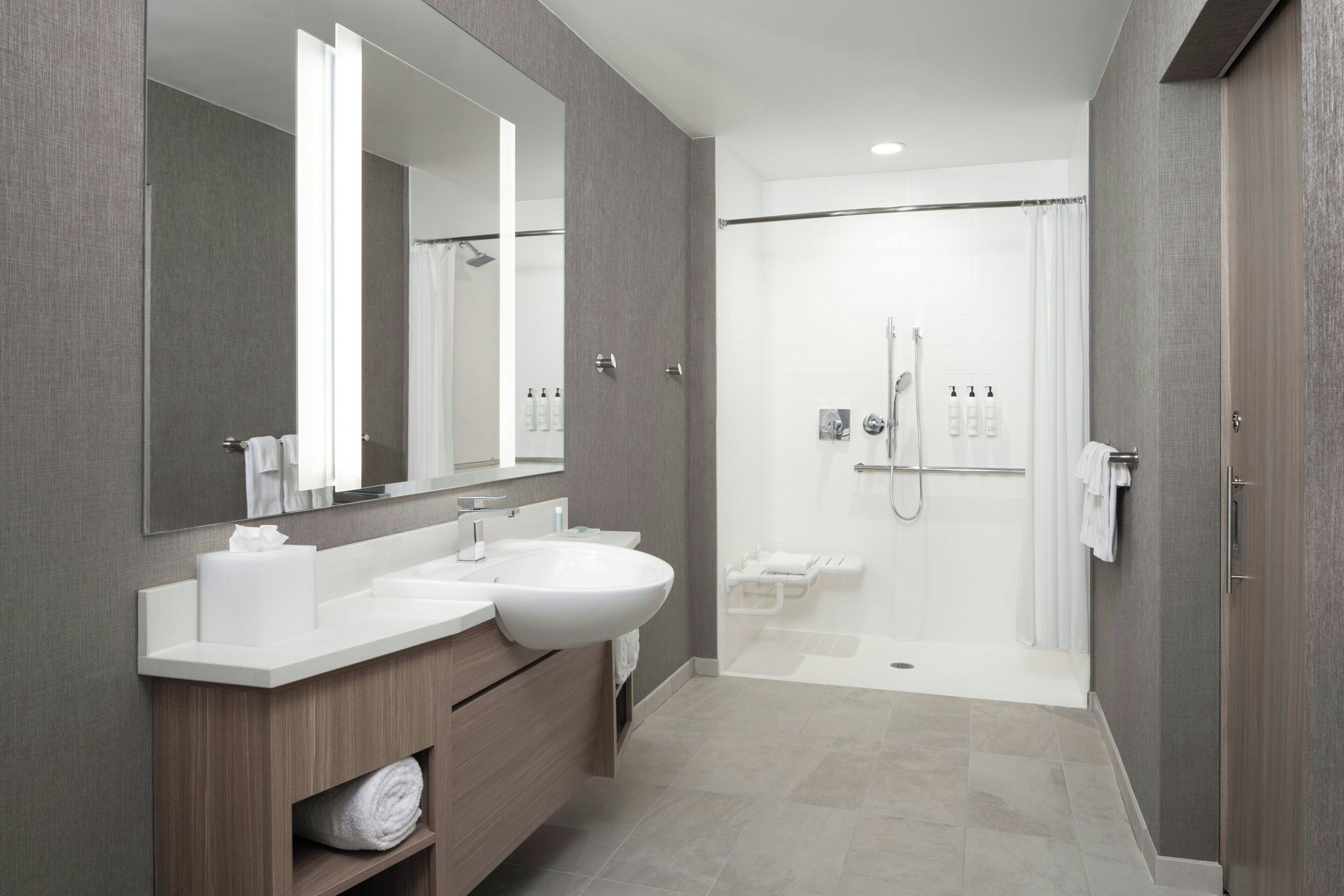 Un baño moderno con dos lavamanos, un espejo grande, zona de ducha y un perchero para toallas.