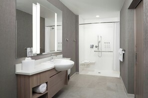 A modern bathroom with two sinks, a large mirror, a shower area, and a towel rack.