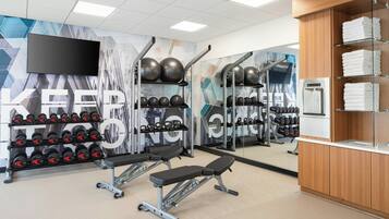 Un gimnasio con equipo de levantamiento de pesas, una banca y un espejo.