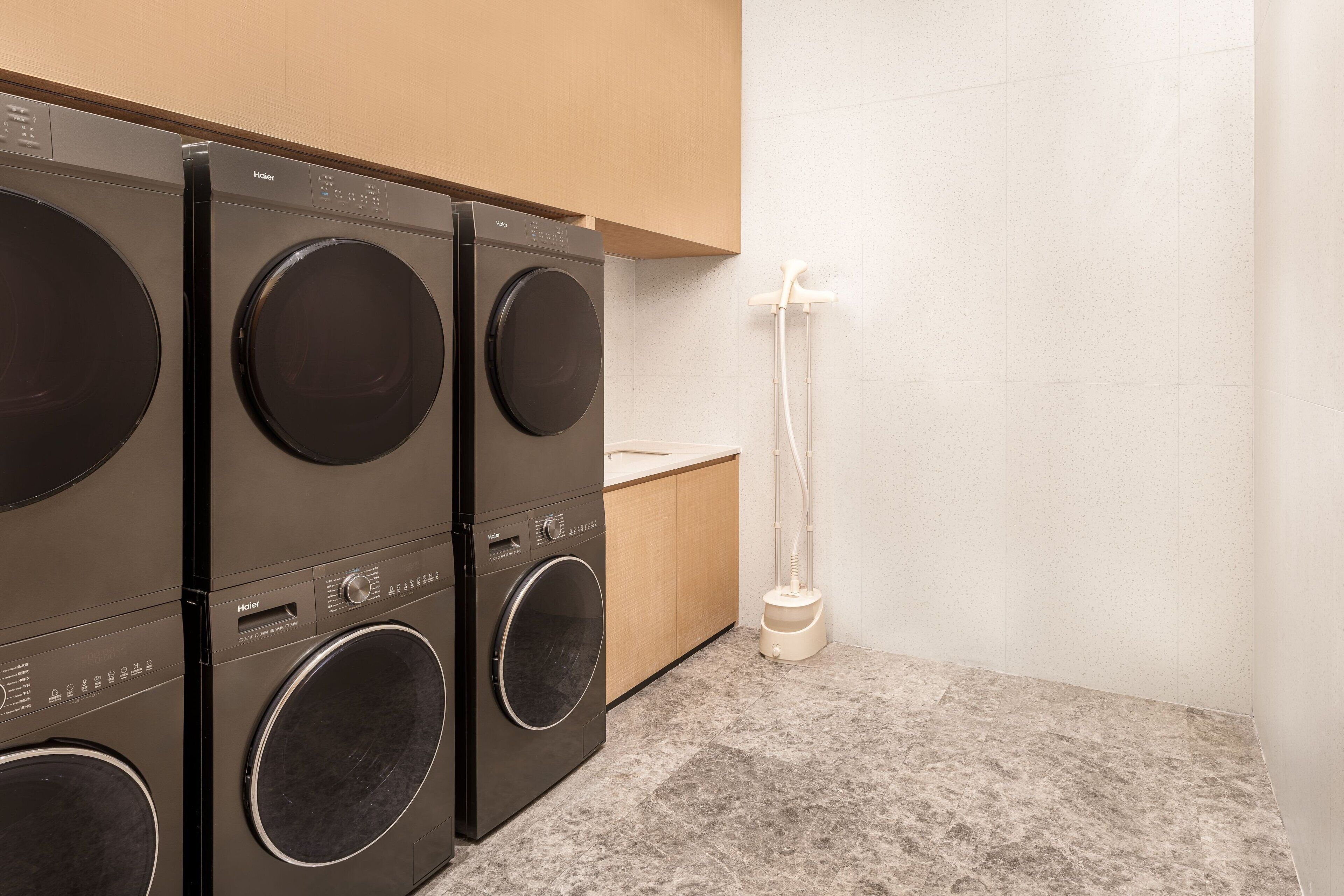 Un área de lavandería con tres lavadoras de carga frontal y un lavabo.