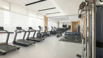 A modern gym with treadmills, weight machines, and dumbbells.