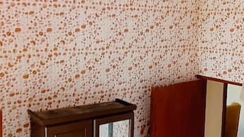 A room with a patterned wall, a wooden cabinet, and a bed with a sheer cover.