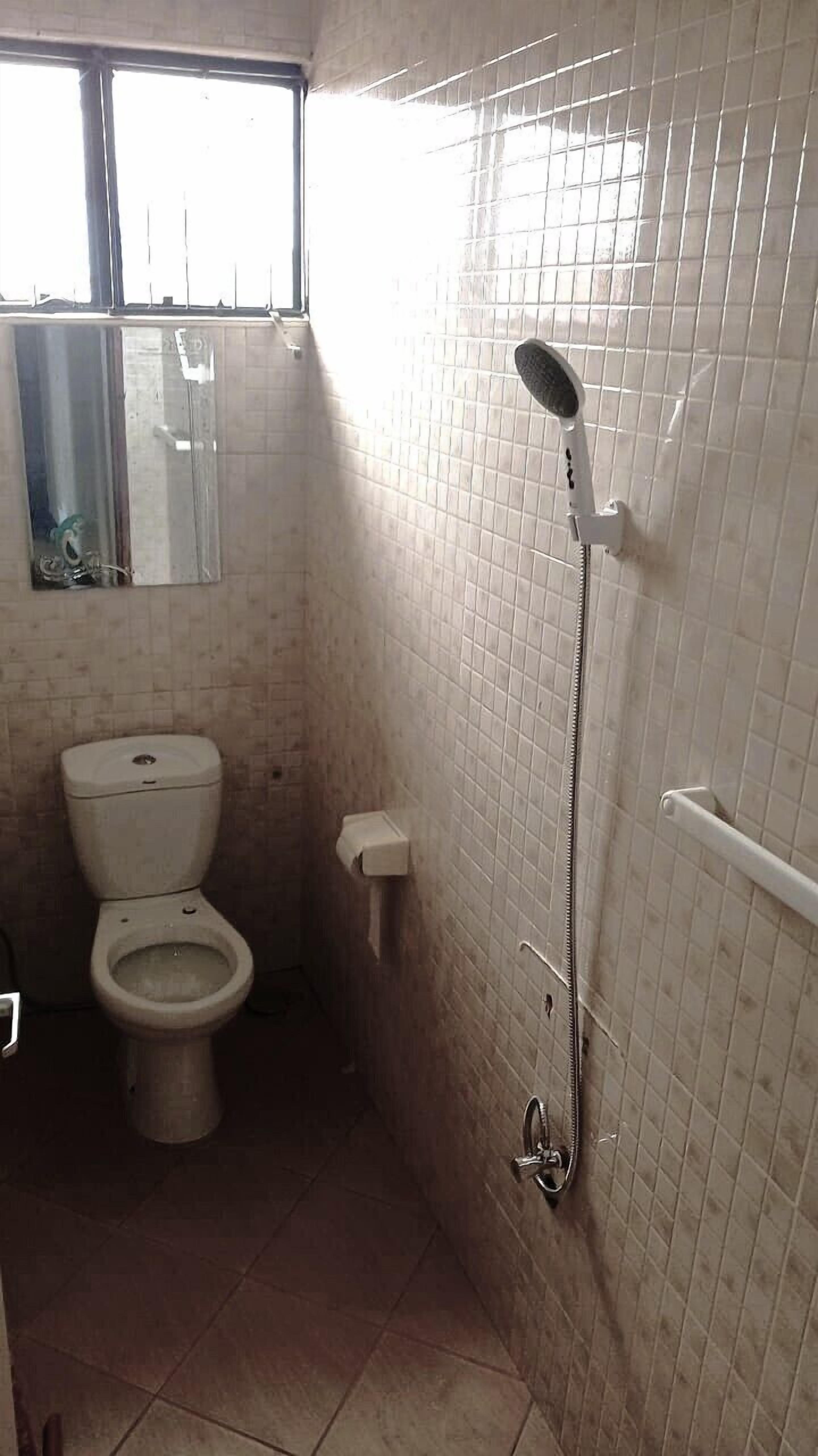 Un baño pequeño con inodoro, ducha y espejo.