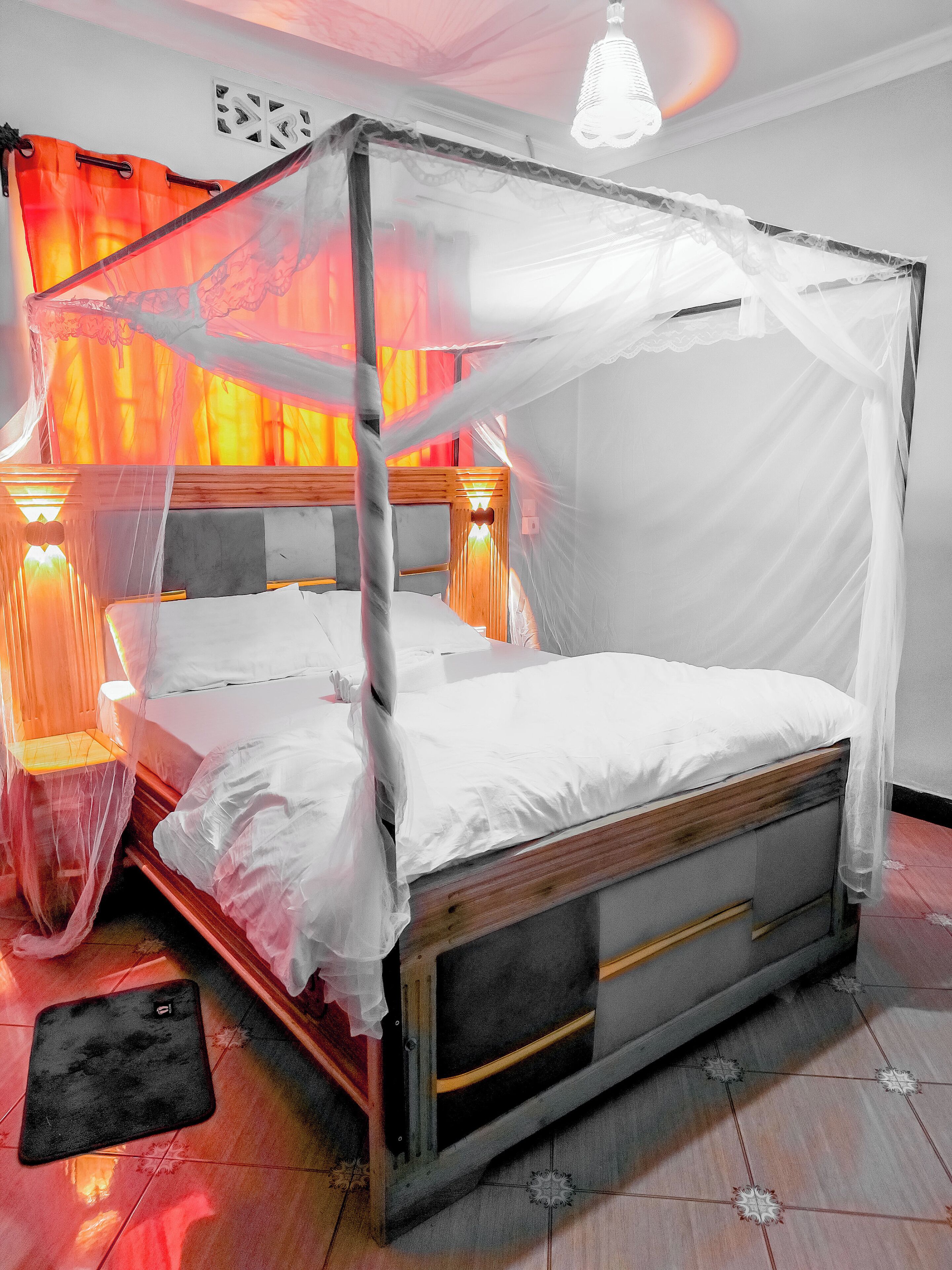 A four-poster canopy bed with white linens, wooden headboard, and bedside lamps.