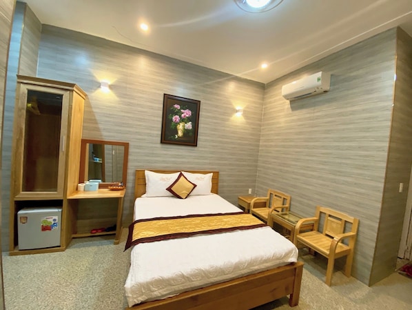 Un dormitorio con cama, escritorio, silla, armario y aire acondicionado.