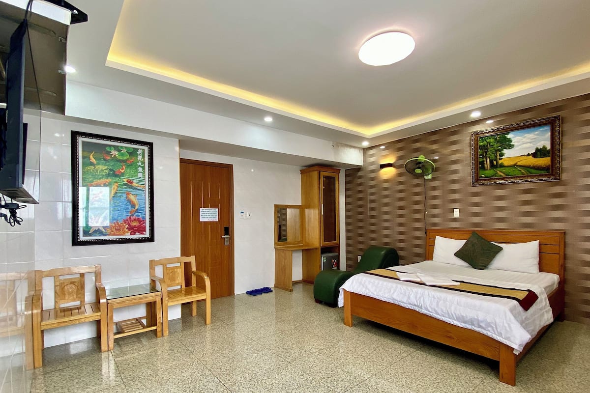 Ein Hotelzimmer mit Bett, Schreibtisch, Stühlen, Fernseher und Bildern an den Wänden.