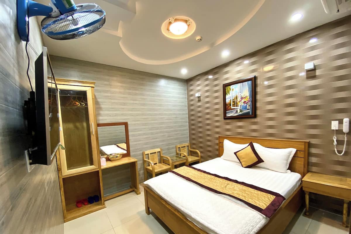 Ein Hotelzimmer mit Bett, Nachttischen, einem Spiegel, einem Kleiderschrank und einem Deckenventilator.