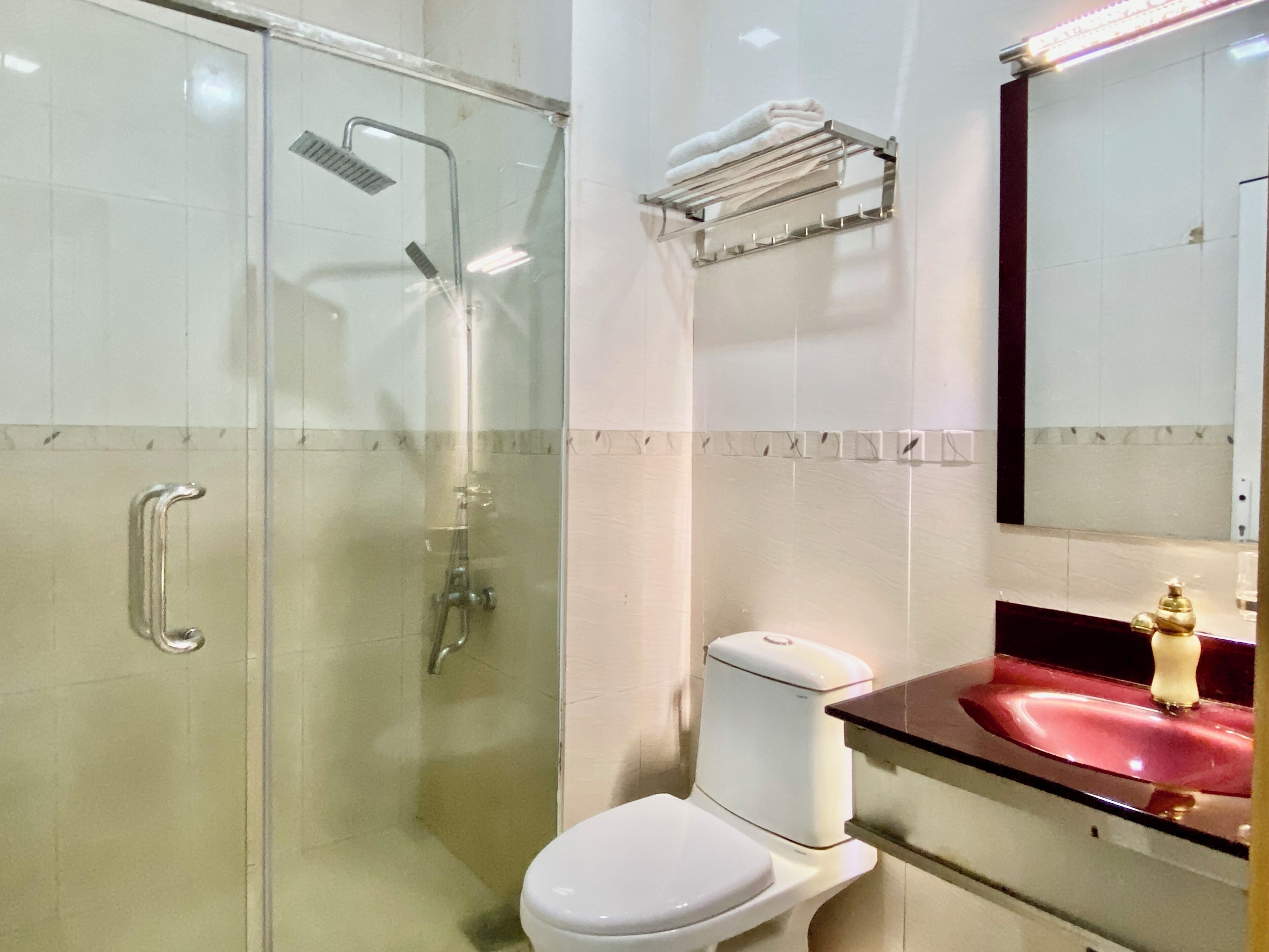 A bathroom with a glass-enclosed shower, a white toilet, and a sink with a marble countertop.