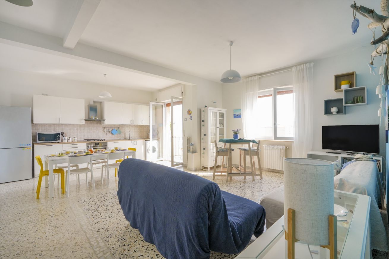 Un grand espace de vie comprenant un canapé, une table à manger avec des chaises, un coin cuisine et un téléviseur.