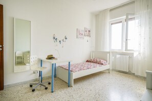 Un dormitorio infantil con cama, escritorio, silla y ventana.