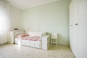 A bedroom with a bed, a chair, a dresser, and a wardrobe.