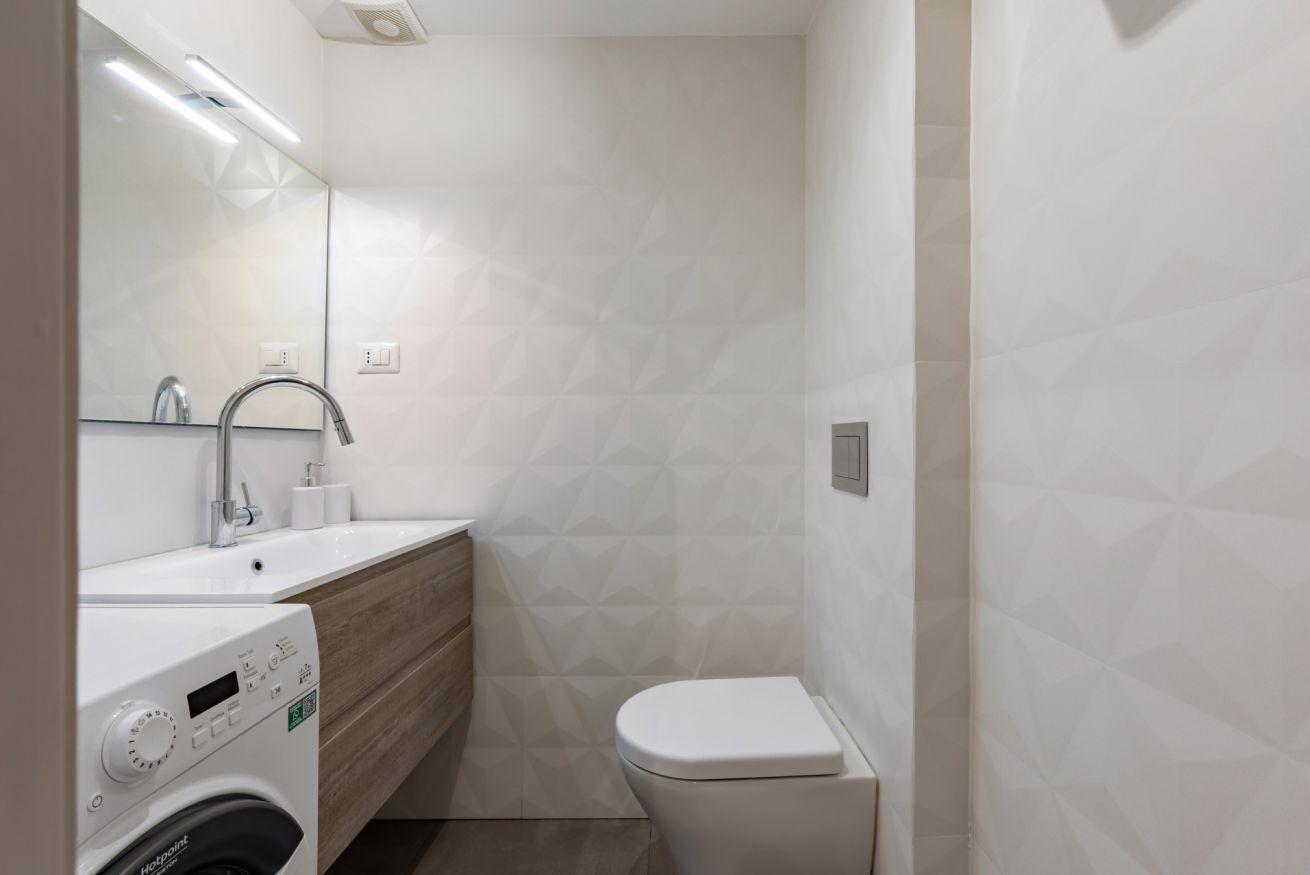 Un baño pequeño con lavadora, lavamanos e inodoro.