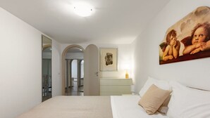 Ein Schlafzimmer mit Bett, Nachttisch, Lampe und einem Gemälde an der Wand.
