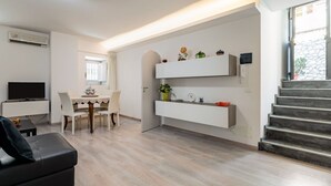 Ein modernes Wohnzimmer mit Flachbildfernseher, einem Esstisch und einer Treppe.