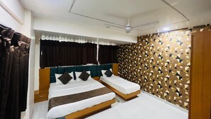 Habitación de hotel con cama doble, cama individual, ventilador de techo y pared con diseño.