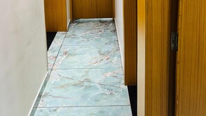 Un pasillo con piso de mármol, puertas de madera y un letrero que dice 'PANTRY' en una puerta.