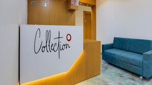 Zona de recepción con un mostrador de recepción identificado como "Collection" y un sofá azul.