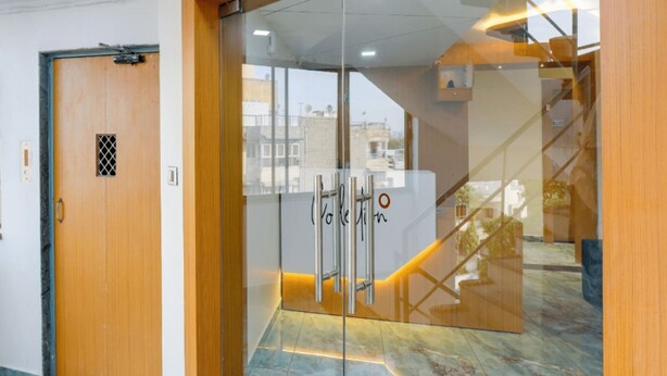 Un interior moderno con una puerta de madera, un muro de cristal y una escalera.
