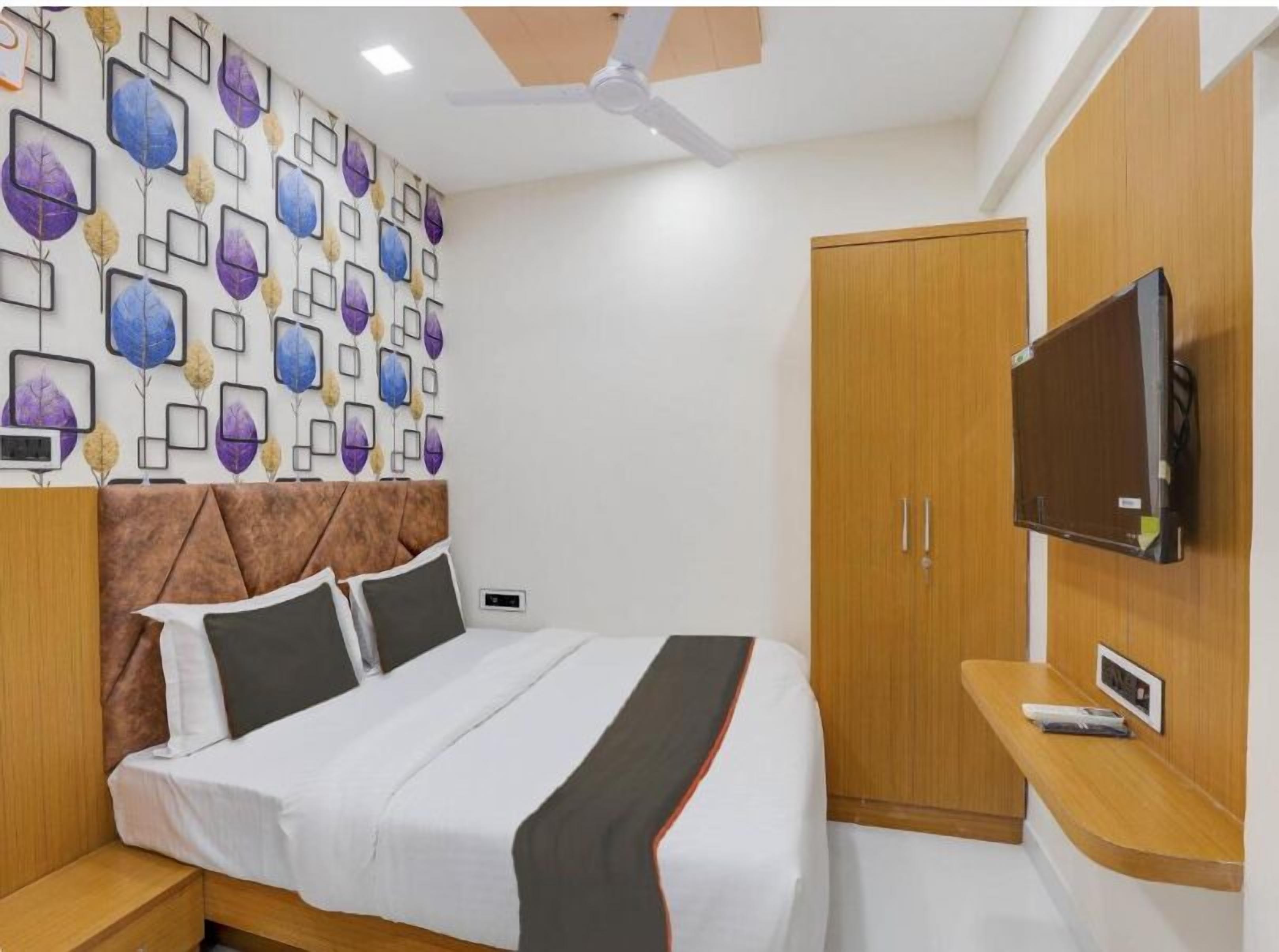 Un dormitorio con cama, armario, televisor montado en la pared y ventilador de techo.