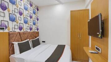 Un dormitorio con cama, armario, televisor montado en la pared y ventilador de techo.
