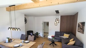 Un salon moderne avec un coin repas, doté d’un plafond en bois, d’un canapé gris et d’une table à manger avec des chaises.