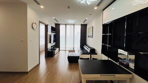 Una sala de estar moderna con comedor, un sofá, un televisor y un amplio ventanal con cortinas.