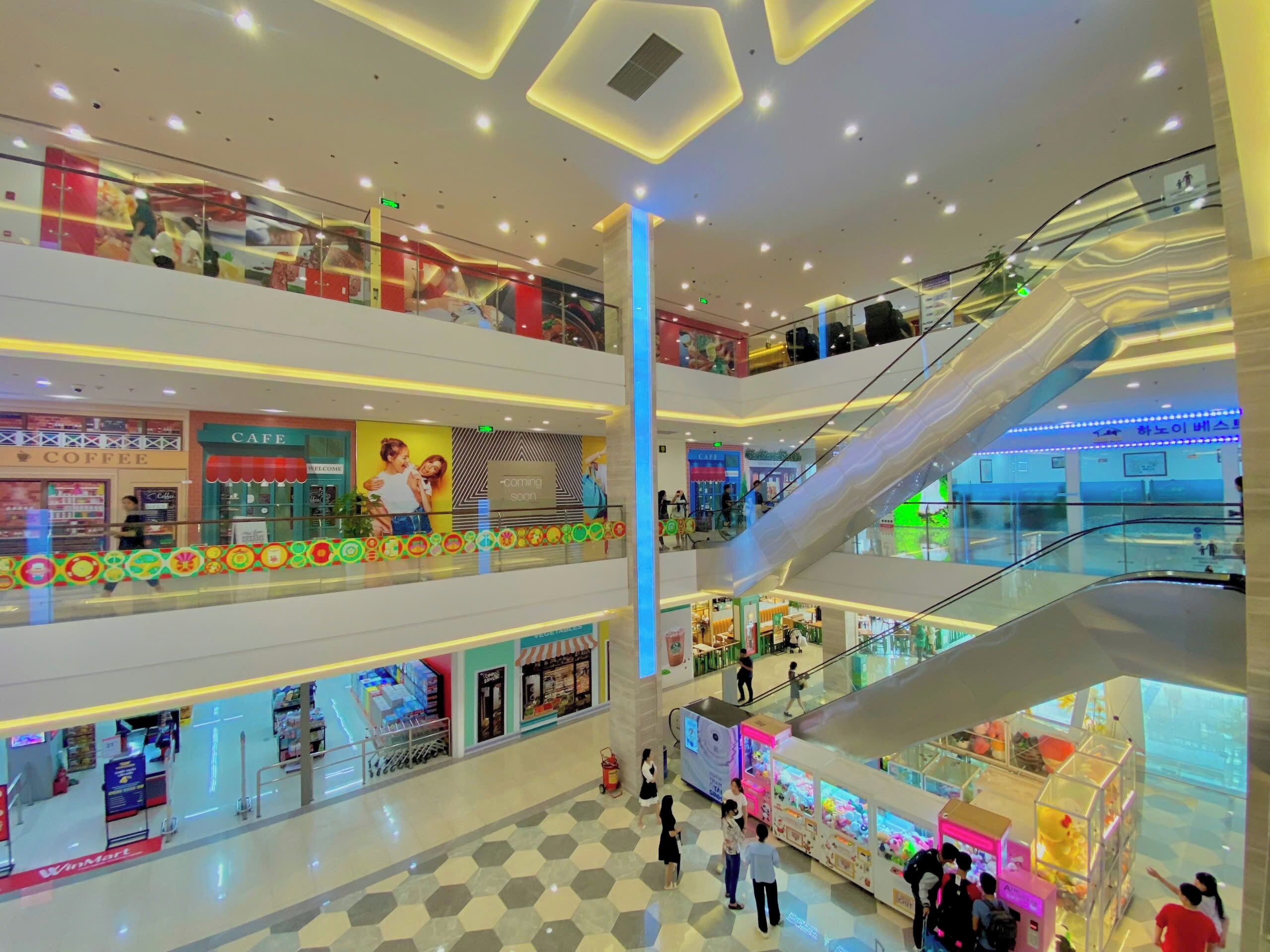 A multi-level shopping mall with escalators, a cafe, and a Womart store.