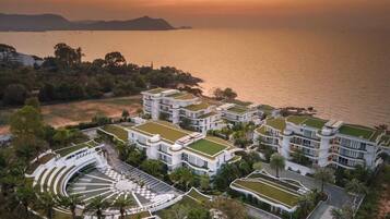 Un hotel frente al mar con varias edificaciones y techos verdes, dispuestas en forma de semicírculo alrededor de un patio central.
