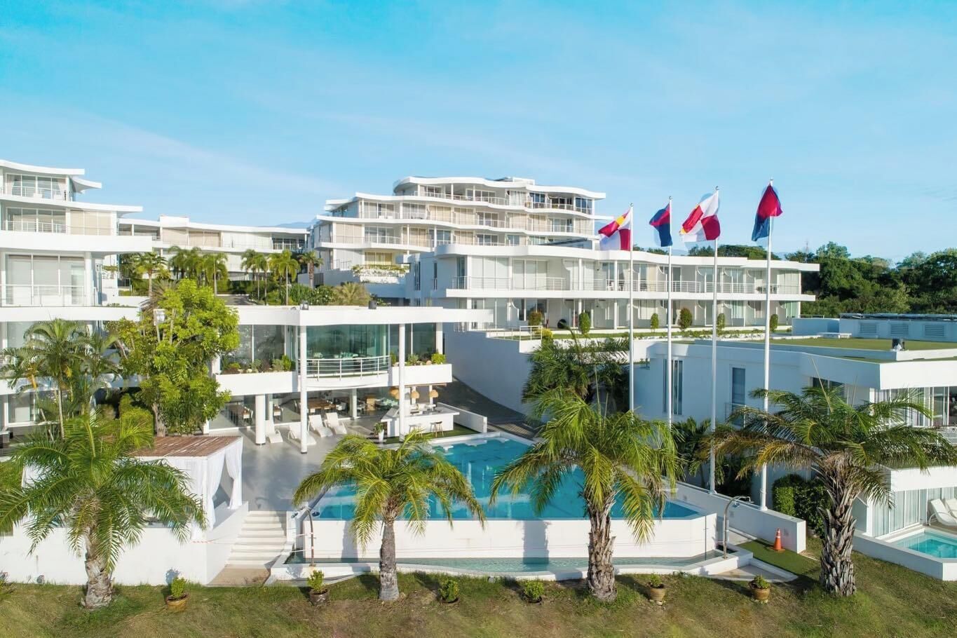 Een modern hotel met meerdere verdiepingen, een centraal gelegen zwembad en verschillende vlaggen.