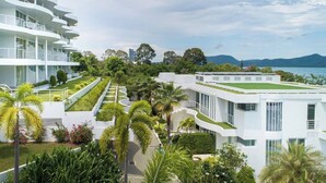 Un hôtel moderne doté de plusieurs étages, de terrasses extérieures et d’une végétation luxuriante.