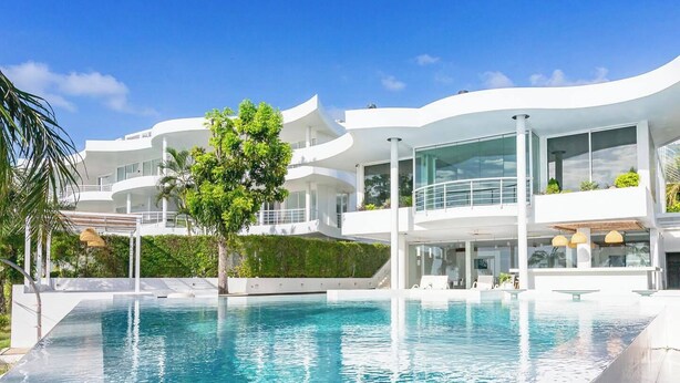 Un bâtiment moderne à plusieurs étages, avec une grande piscine à débordement bien visible au premier plan.