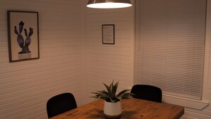 Un comedor con una mesa de madera, sillas negras, una lámpara colgante y una planta en maceta.