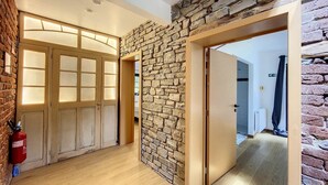 Un pasillo con pared de piedra, puertas de madera y un extintor.