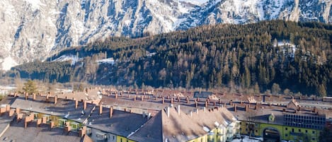 A town with traditional architecture, a central yellow building, and a mountain backdrop.