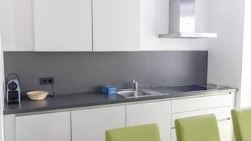 A modern kitchen with white cabinets, a grey countertop, a stainless steel sink, and a built-in range hood.