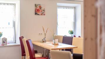 A dining area with a wooden table, red and beige chairs, and two vases with dried plants.
