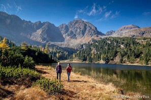 A mountainous landscape with a lake and two people walking.
