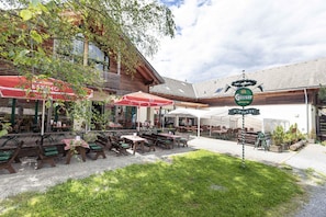 An outdoor seating area with tables and chairs, a sign for 'Güssler', and a 'S'Platzli' sign. - Attractive studio with balcony (Kreischberg Murau)