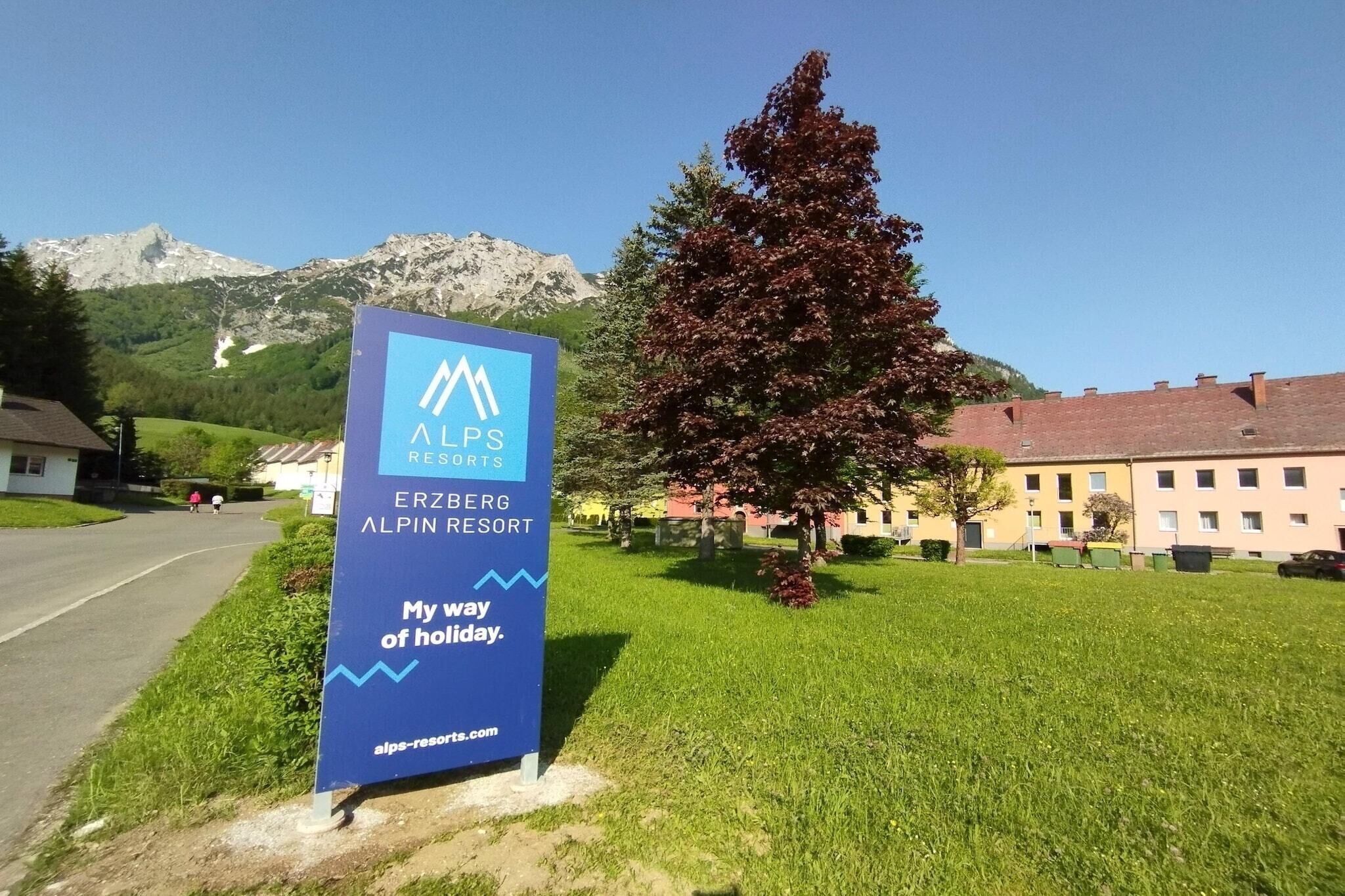 Schild für das Erzberg Alpen Resort vor einer Bergkulisse.