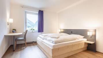 Un dormitorio con cama de madera, un escritorio y una ventana con vistas a montañas.