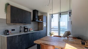 Een moderne keuken met donkere kastjes, een houten aanrecht en een zithoek met een houten tafel en stoelen.