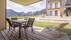 A wooden deck with a table and chairs, overlooking a mountainous landscape.