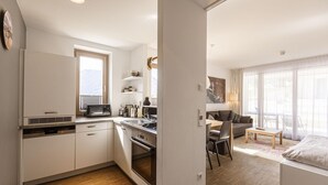 A compact apartment with a kitchenette, a dining area, and a living space with a sofa and a bed.