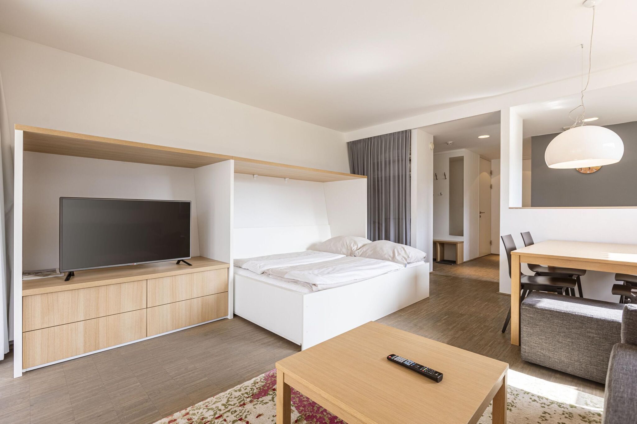 Een moderne hotelkamer met een bed, een televisie, een bureau en een zithoek.