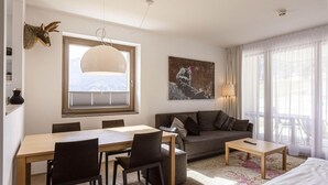 A modern living room with a dining area, a sofa, a coffee table, and a mounted animal head.