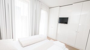 A hotel room with a bed, a TV mounted on the wall, and a wardrobe. - Lush apartment with private sauna (Schladming - Rohrmoos)